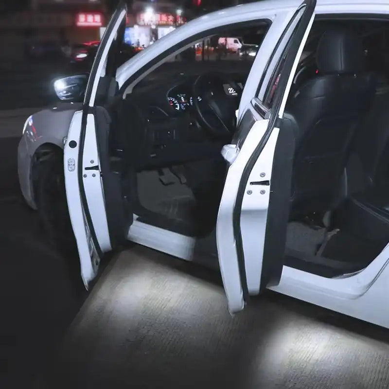 Car interior with open doors at night, illuminated by a light source.