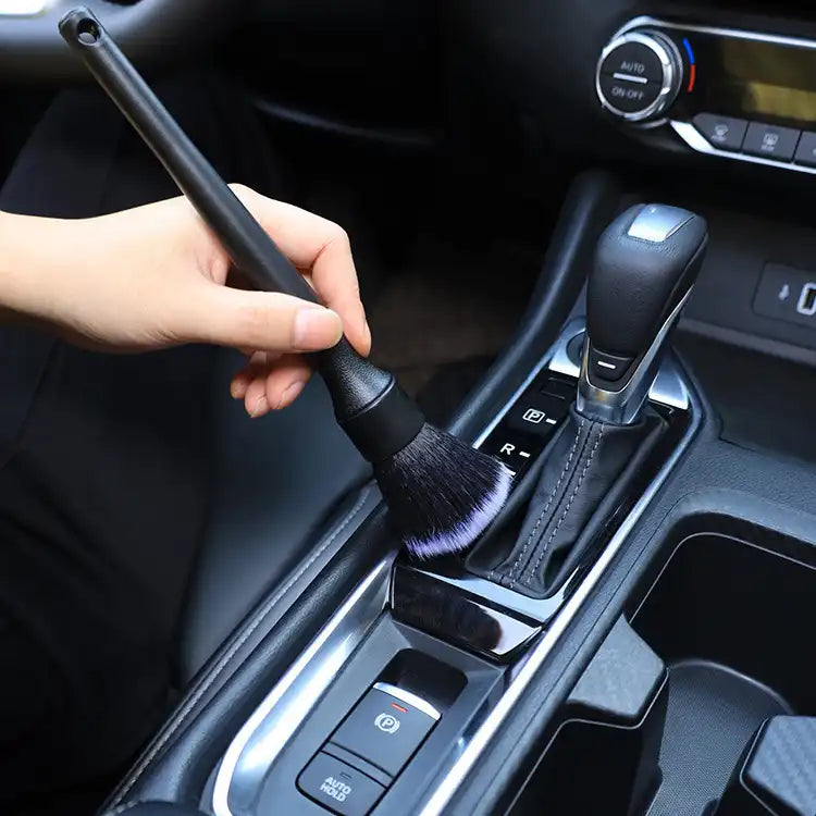 Car interior cleaning brush being used to clean a car's gear shift area.