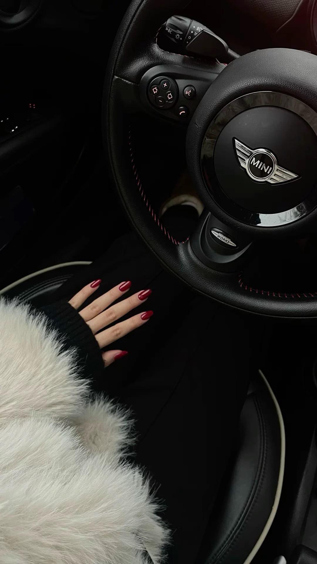 Steering wheel with a hand touching the air vent in a car interior, featuring the Mini logo.