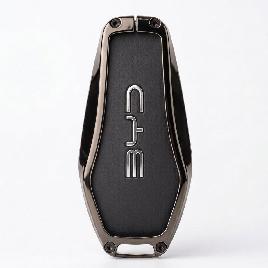 A sleek, metallic dark gray key fob or keychain with a textured black center panel featuring the vertical silver logo BYD. The product is photographed on a clean, light gray background with a soft shadow underneath.