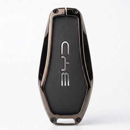 A sleek, metallic dark gray key fob or keychain with a textured black center panel featuring the vertical silver logo BYD. The product is photographed on a clean, light gray background with a soft shadow underneath.