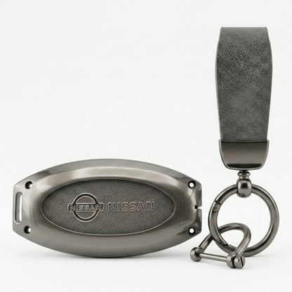 A dark gray NISSAN JUKE leather key fob cover & strap attached to a matching dark gray metal keychain ring and oval tag, shown on a clean white background.
