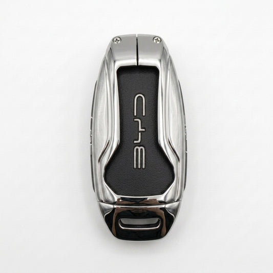 A luxury BYD METAL KEY COVER with a polished silver metallic exterior and a black textured center panel featuring the stylized BYD logo