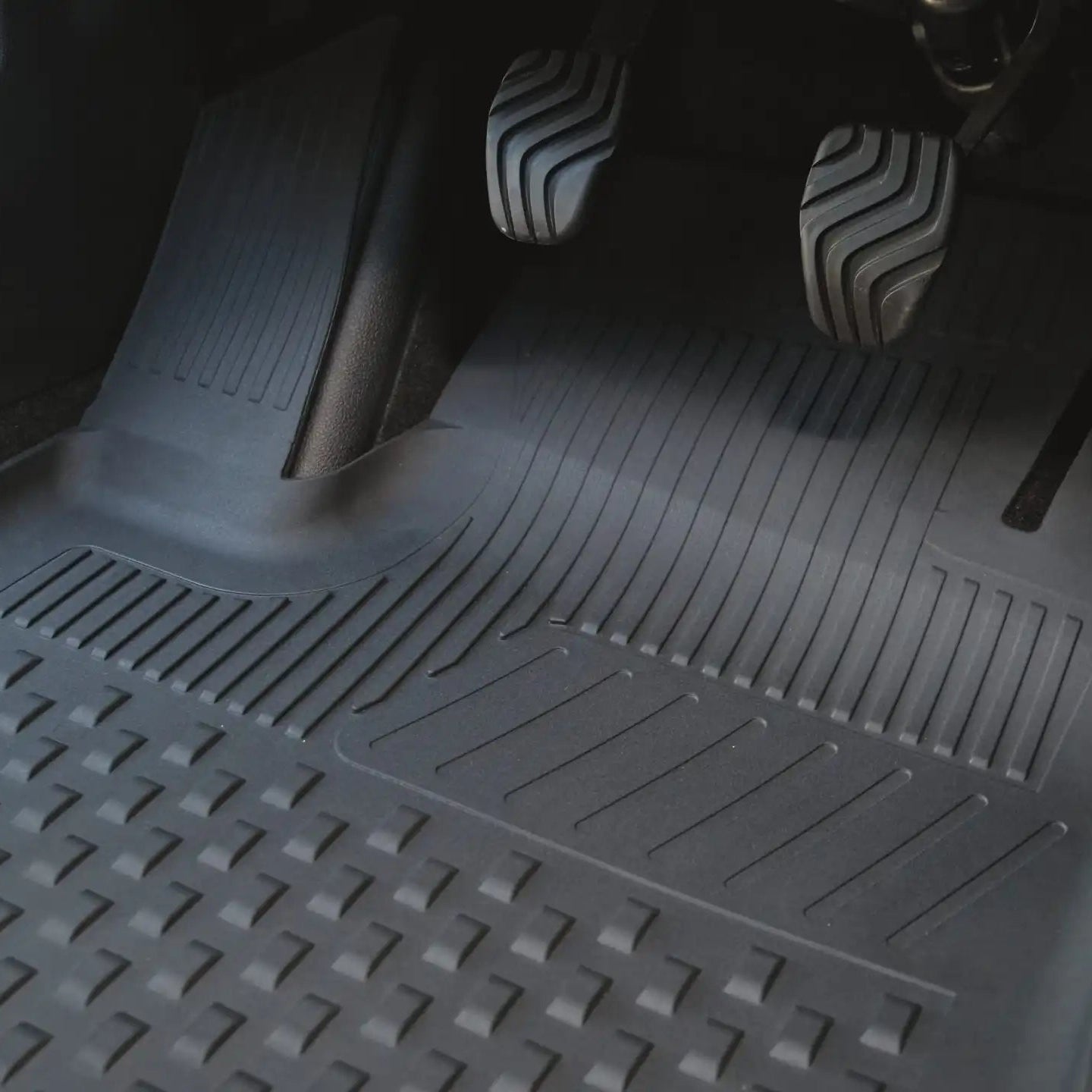 Car interior with a detailed view of the floor mat and pedals.